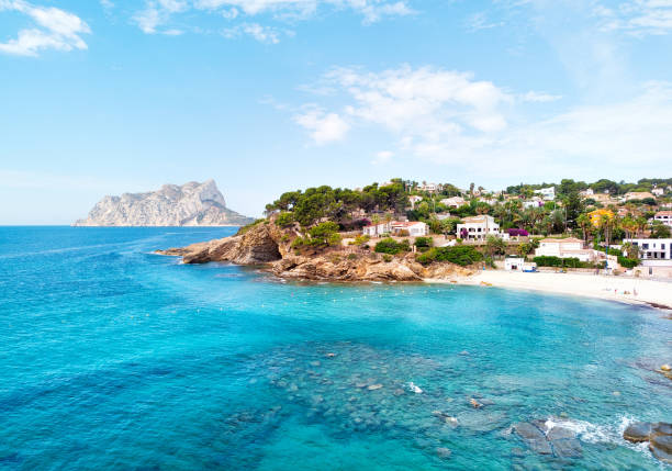 Turquoise bay of Mediterranean Sea of Benissa spanish resort town Turquoise bay of Mediterranean Sea of Benissa spanish resort town. White sand on the beach, hillside houses. Province of Alicante, Costa Blanca, Spain benissa stock pictures, royalty-free photos & images