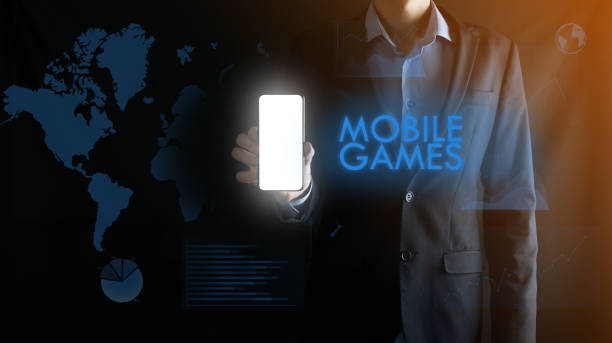 istock Businessman holding a mobile smartphone with white blank screen with space for text ,inscription word MOBILE GAMES.Business, Technology, Internet and network concept 1285140403