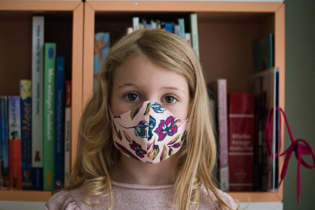 istock Female Child Wearing Protective Face Mask Looking at Camera 1285142631