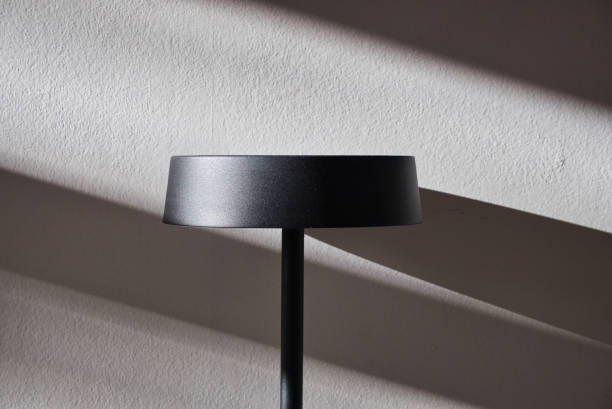 istock Metal Lampshade on White Wall with Daylight Shadows 1285142699