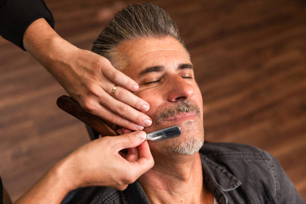 barber's hands about to shave a customer's beard with a razor the hands of a Caucasian barber about to shave a client's beard with a classic razor in the barber shop. switchblade stock pictures, royalty-free photos & images