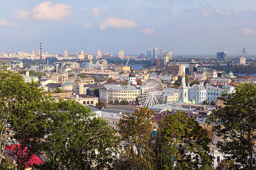 Scenic view of ancient Square of Contracts (Contract Square) with Ferris wheel in the Podil district. Skyscrapers in Obolon neighborhood on the background. Autumn morning cityscape of Kyiv downtown.