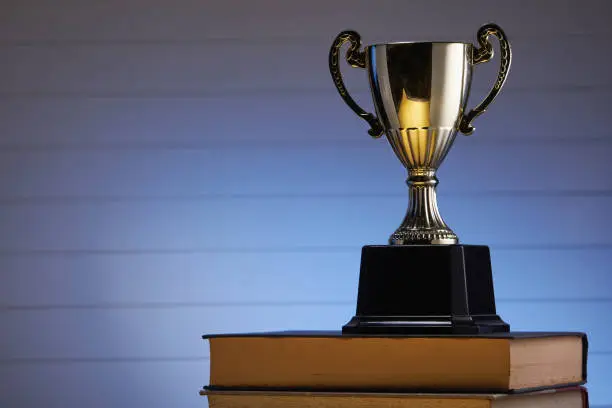 Photo of Golden trophy and book, learning and achievement concept