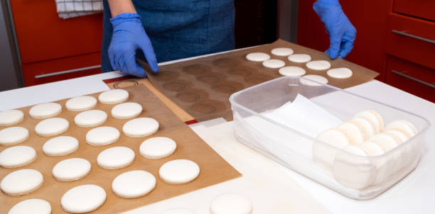 pastry chef hands holding the parchment with the raw macaron. cooking process. - fragility organization chef cake imagens e fotografias de stock