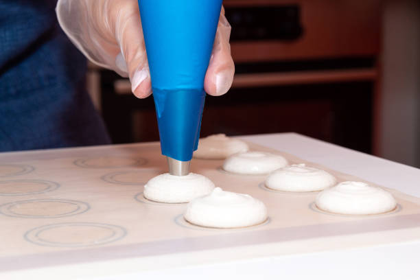 spread the dough from the pastry bag on parchment for baking. the process of making dessert-macaroons. - fragility organization chef cake imagens e fotografias de stock