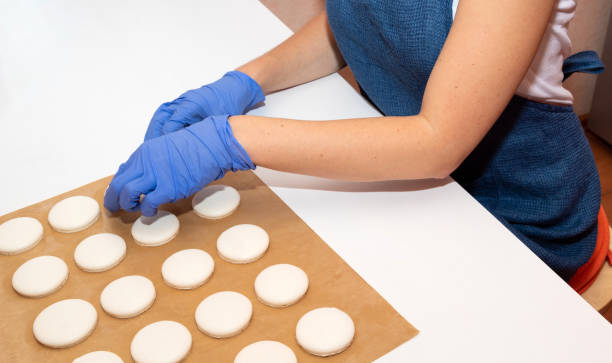 hands tear off the finished macaroons from the parchment after baking. - fragility organization chef cake imagens e fotografias de stock