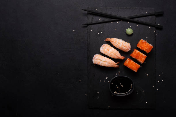 istock sushi with tiger shrimp and rolls on black board 1285148230