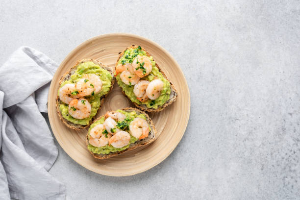 bruschetta toast con avocado e gamberetti - sandwich avocado prepared shrimp bread foto e immagini stock