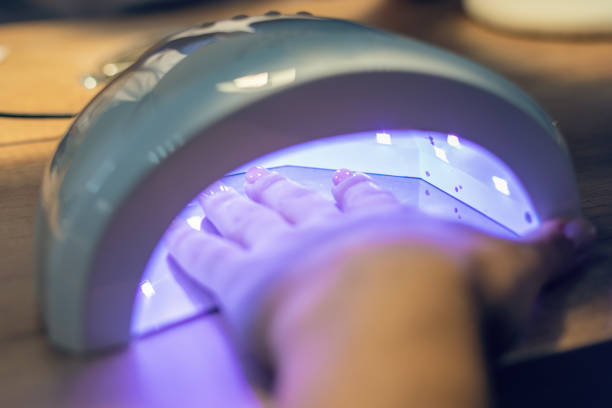 istock Girl dries her nails covered with gel polish using a UV lamp 1285151063