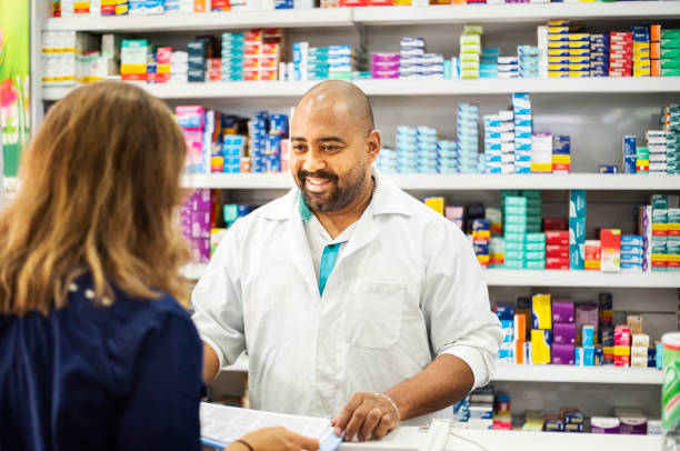 I'll be happy to help you manage your health Friendly pharmacist assisting female customer at drug store pharmacy photos stock pictures, royalty-free photos & images