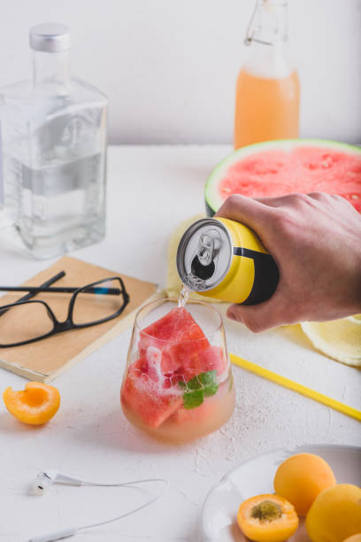 Red cocktail with frozen watermelon cubes, gin and soda Red cocktail with frozen watermelon cubes, gin and soda. Hand pour soda into the drinking glass russian culture audio stock pictures, royalty-free photos & images