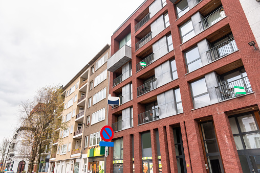 Modern apartment buildings with shops on the ground levels on a cloudy day. Some of the apartments have real estate signs. Antwerp, Belgium.