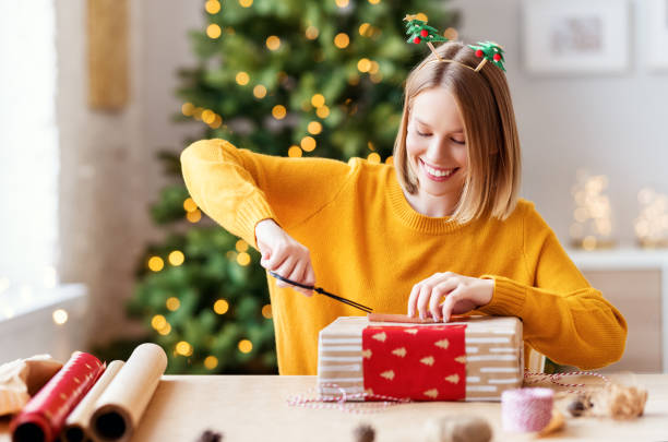 istock Cheerful woman decorating gift box on Christmas day 1285171875
