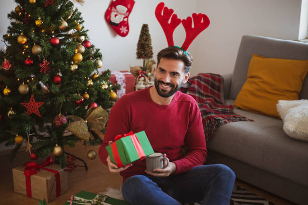 istock A beautiful young man opens New Year's presents under the Christmas tree 1285173947