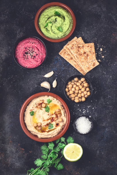 istock Flat lay of various types of vegetarian hummus based on herbs and beets, basil and coriander on a dark rustic background 1285174085