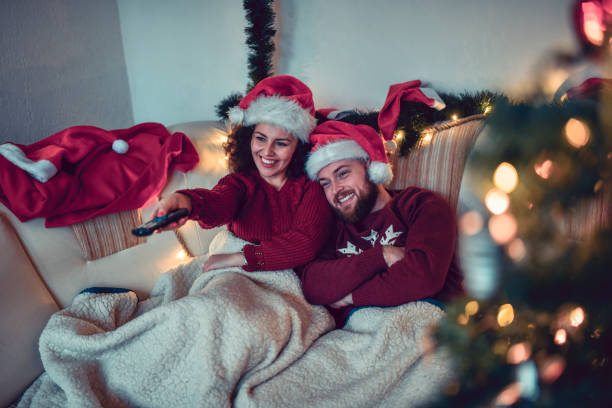 cute couple enjoying christmas with tv and movie under the blankets - remote television movie box imagens e fotografias de stock
