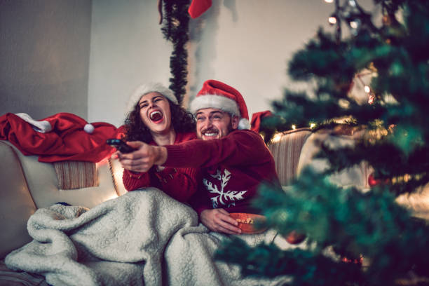 couple watching a movie on christmas eve in bed - remote television movie box imagens e fotografias de stock
