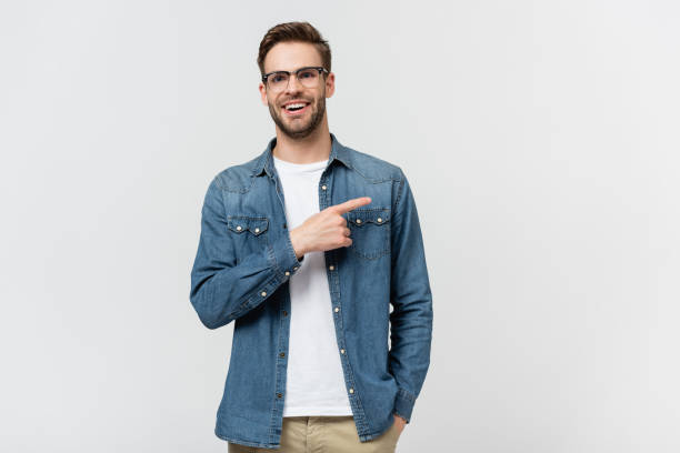 istock Positive man in eyeglasses pointing with finger away isolated on grey 1285176370