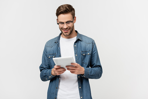 Smiling man in eyeglasses holding digital tablet isolated on grey