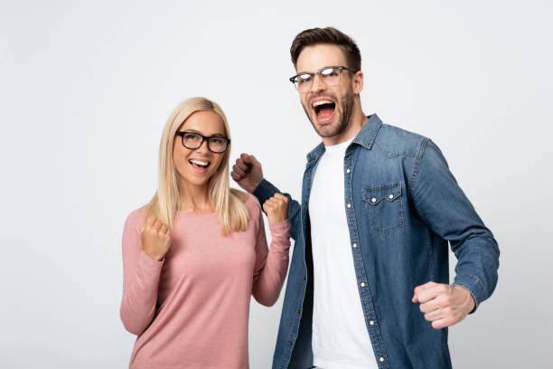 istock Excited couple in eyeglasses showing yeah gesture isolated on grey 1285176374
