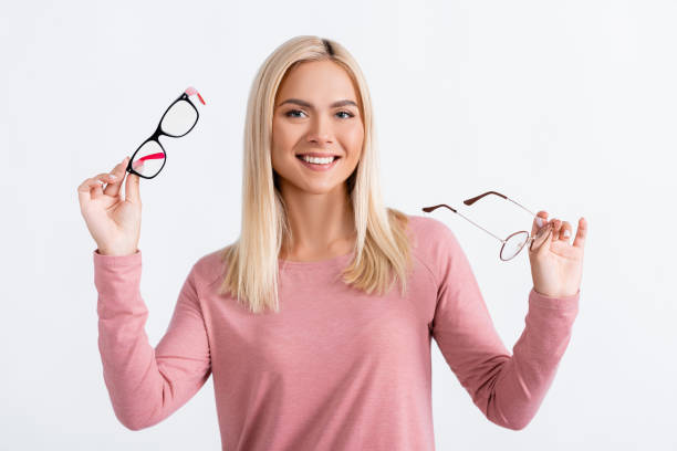 istock Positive woman looking at camera while holding eyeglasses isolated on white 1285176414