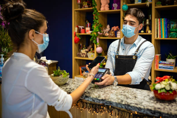 woman who uses mobile payment with a smartphone in a flower shop - cell human cell plant cell virus imagens e fotografias de stock
