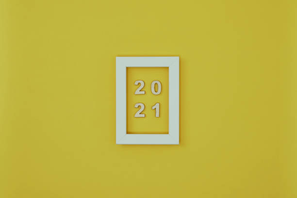 istock White frame with New Year decorations and the inscription 2021 on a yellow background. New Year backgrounds. Copy space, mock up 1285182421