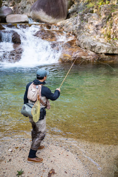 istock Man Fly Fishing in a mountain river with a waterfall 1285185712