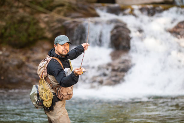 istock Man Fly Fishing in a mountain river with a waterfall 1285185727