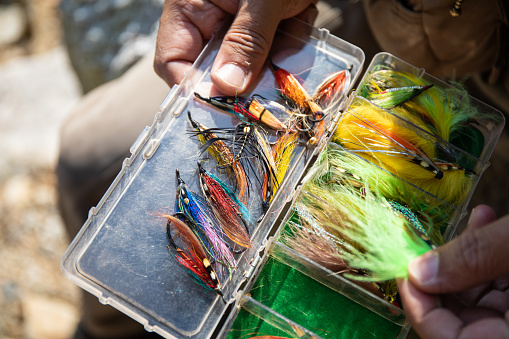 A man holding and choosing from a big selection of his Fly Fishing hooks close up.