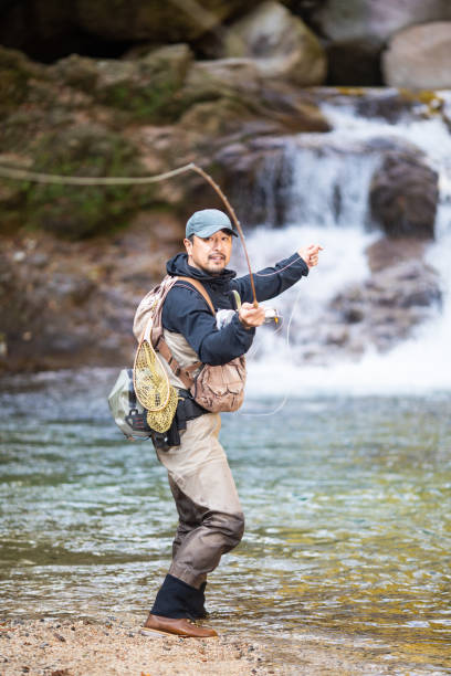 istock Man Fly Fishing in a mountain river with a waterfall 1285185741