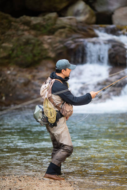istock Man Fly Fishing in a mountain river with a waterfall 1285185749
