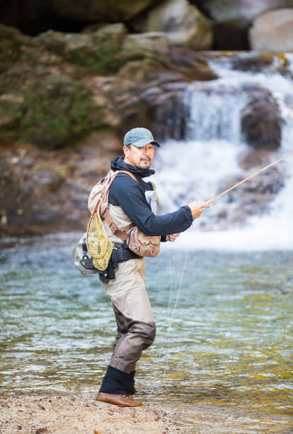 istock Man Fly Fishing in a mountain river with a waterfall 1285185756