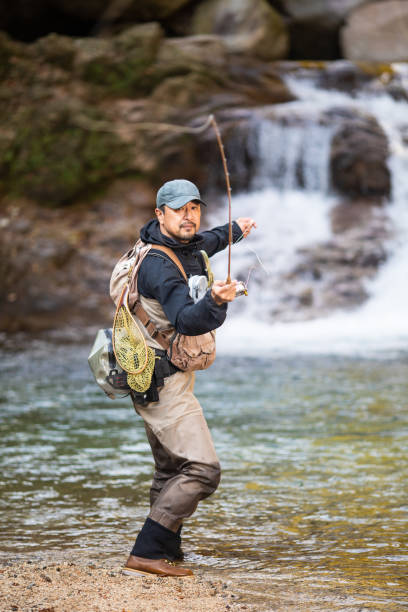istock Man Fly Fishing in a mountain river with a waterfall 1285185762
