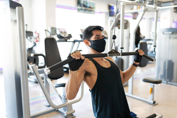 istock Young man with a mask exercising in the cable machine 1285186695