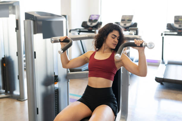 istock Young woman working out on a shoulder press machine 1285187547