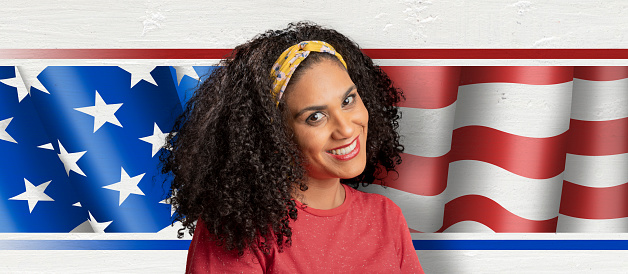 Latin american woman smiling in front of american flag