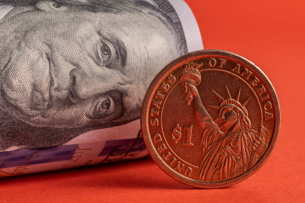 istock 1 American dollar coin and rolled 100 American dollars 1285190603