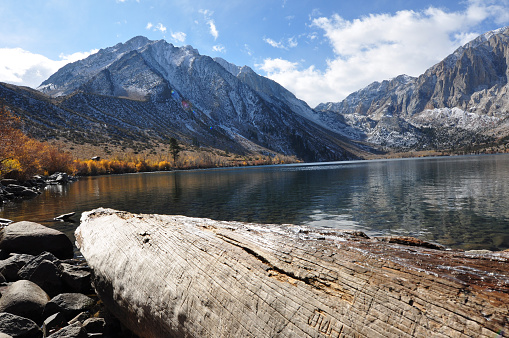 Pretty fall colors, a big log, a fishing boat and reflections at Convict lake on a cloudy day in the autumn