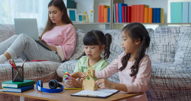 istock Young woman working with laptop two daughters playing at home. 1285200272