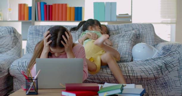 istock Young mother while working at home with two daughters naughty 1285200274