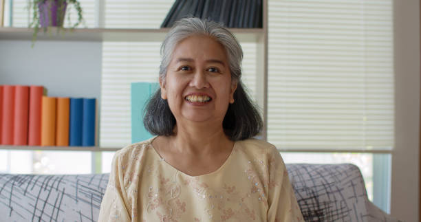 istock Senior woman sitting on sofa smile and looking to camera 1285200310