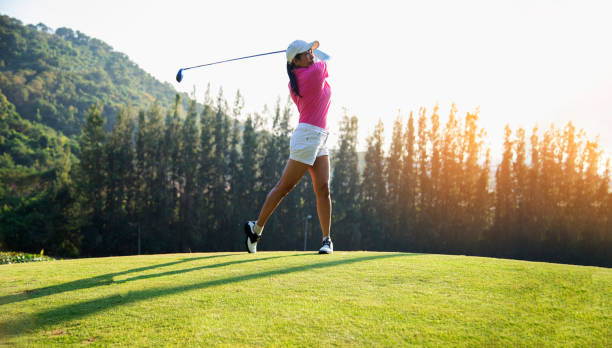 glücklich und fröhlich von der golfspielerin beim gewinnen putt einen ball in das loch auf dem grün abgeschlossen - golf golf flag sunset flag stock-fotos und bilder