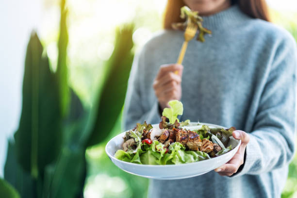 istock a woman holding and eating chicken salad 1285206839
