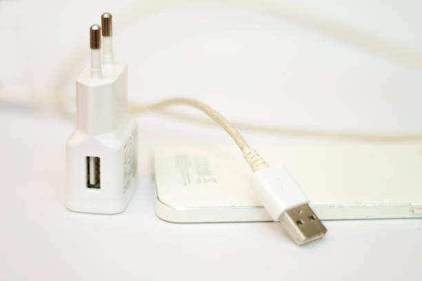 istock Modern white smartphone and phone charge with power cord isolated on the white background 1285210357