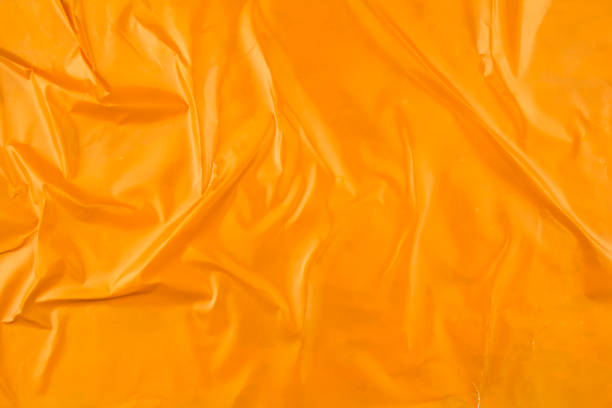 istock Crumpled glossy orange magazine paper poster background. 1285212831