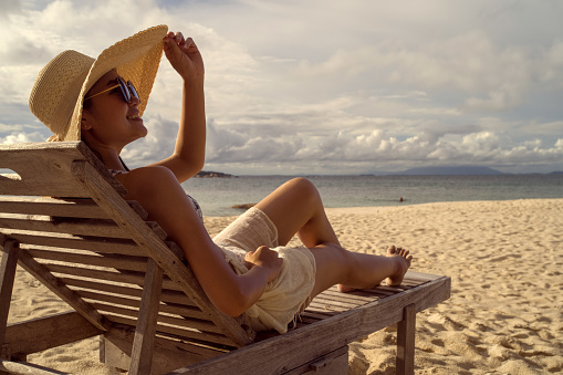 4K Asian woman Sit in a chair Mobile living at the beach on a clear day