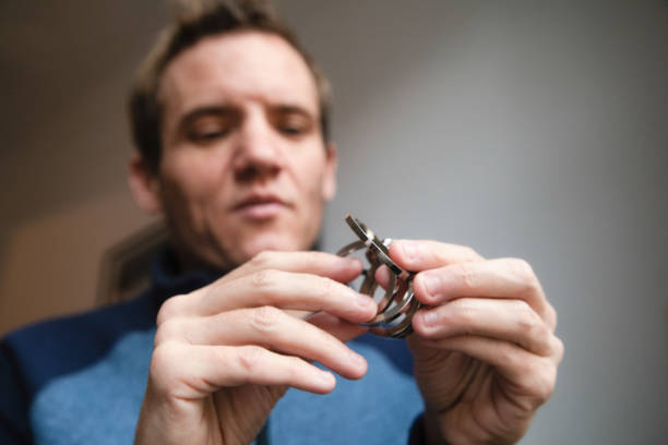 primer plano en las manos masculinas autistas tratando de resolver un rompecabezas de metal - nail biting biting fingernail obsessive fotografías e imágenes de stock