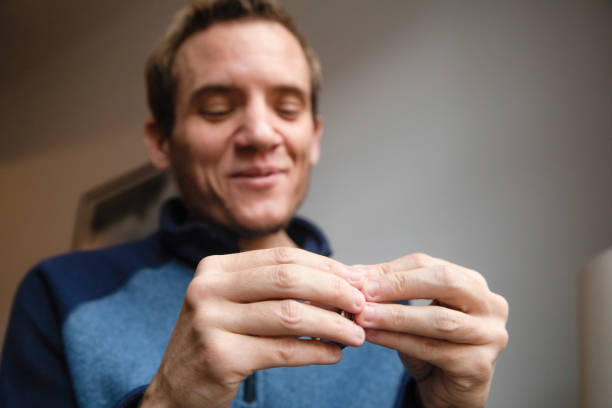 primer plano en las manos de un macho sonriente autista tratando de resolver un rompecabezas de metal - nail biting biting fingernail obsessive fotografías e imágenes de stock