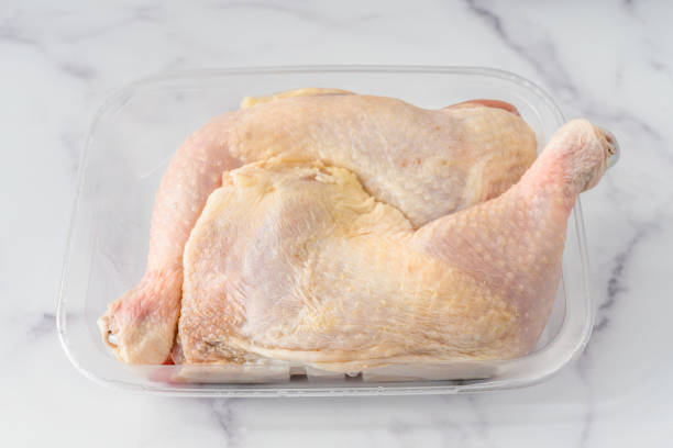 istock Chicken leg quarters in plastic container close up on marble background 1285215031